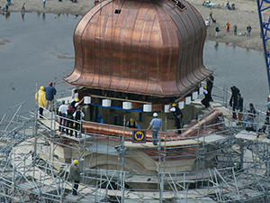 Arbeiter bei der Aufsetzung der Kuppel mittels Kran